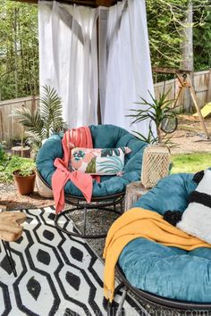 an outdoor area with chairs, rugs and pillows on the ground in front of a gazebo