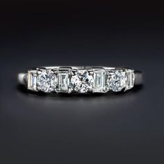 a five stone diamond ring with baguetts set in white gold on a black background