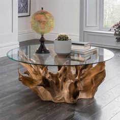 a glass table topped with a wooden piece of wood next to a plant and a globe