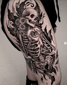 a woman's thigh with a skeleton and flowers tattoo on it