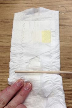 a person holding a piece of cloth with a wooden stick sticking out of it on top of a table