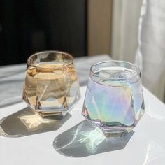 two glass vases sitting on top of a white table