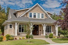 a house that is in the middle of some grass and bushes with trees around it