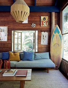 a living room with a couch, coffee table and surfboard on the wall next to it