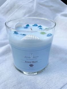 a candle that is sitting on top of a white cloth with sea shells in it