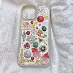 a cell phone case with many different things on the front and back cover, sitting on top of a white sheet