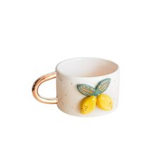 a coffee cup with two lemons on the side and a gold ring around it