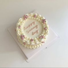 a white cake with pink roses on it sitting on top of a box that says happy birthday you