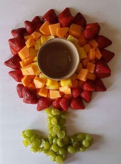 fruit arranged in the shape of a sunflower with a bowl of chocolate sauce on top