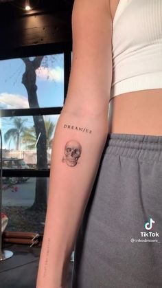 a woman's arm with a skull tattoo on the left side of her arm