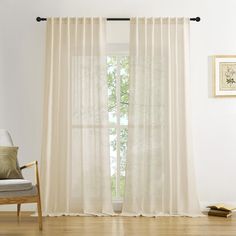 a living room with white curtains and a chair