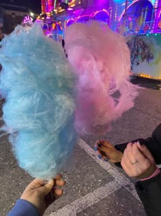 two people are holding cotton candy in their hands