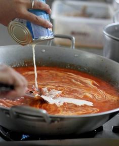 someone pouring sauce into a pan on the stove