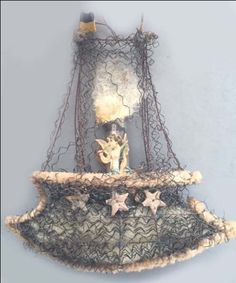 an old fashioned hanging basket with angel figurines on it's sides and wire netting around the edges