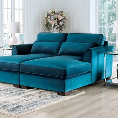 a large blue couch sitting on top of a wooden floor next to a table and lamp