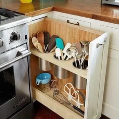 an organized kitchen shelf with utensils and spoons in it next to the oven