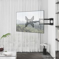 a living room with white curtains and a large tv mounted to the wall above it