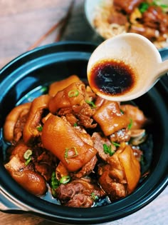 a person pouring sauce on food in a bowl