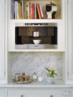 a kitchen with white cabinets and bookshelves filled with books on top of them