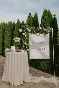 a table set up for a wedding with flowers on it and a sign that says ollivia conner