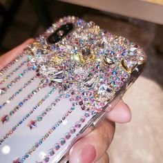 a person holding a cell phone covered in lots of diamonds and jewels on it's back