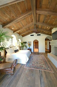 a bedroom with wood floors and white bedding in the center, along with an area rug on the floor