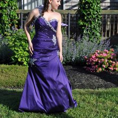 a woman in a purple dress standing on the grass