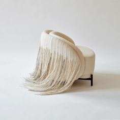 a white chair with fringes on it sitting in front of a white wall and floor