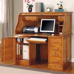 a computer desk with drawers and a monitor on it's stand in front of a window