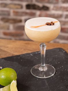 a drink sitting on top of a table next to limes