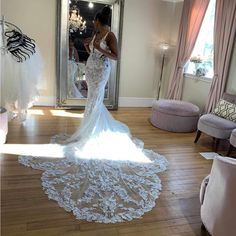 a woman standing in front of a mirror wearing a wedding dress