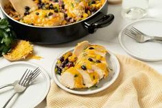 a white plate topped with chicken and black beans next to a skillet filled with cheese