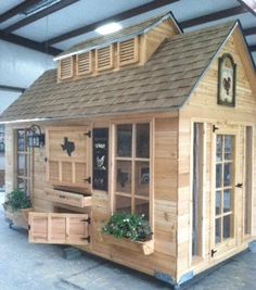 a small wooden house sitting inside of a building with windows and doors on the roof