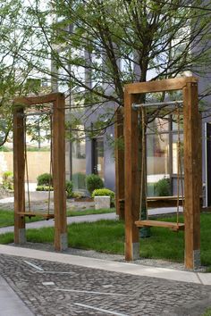 three wooden benches sitting next to each other on top of a grass covered park area