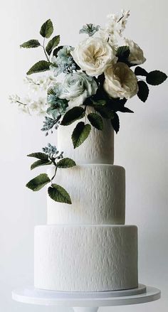 a three tiered white cake with flowers on top