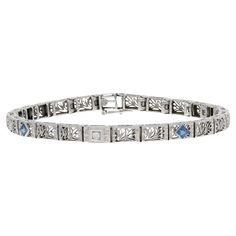 Era: Art Deco 1920s - 1930s Metal Content: 14k White Gold Stone Information: Synthetic Sapphires Carats: .50ctw Cut: Square Color: Blue Natural Diamond Carat: .02ct Cut: Old European Color: H Clarity: VS2 Total Carats: .52ctw Bracelet Style: Link Fastening Type: Tab Box Clasp with Side Safety Clasp Features: Filigree & Milgrain Detailing Measurements: Length: 7" Width: 7/32" (4.8mm) Total Weight: 10.7 Grams Stamps: 14k Condition: Pre-Owned Condition Note: Professionally Cleaned and Polished Luxury Art Deco Jubilee Bracelet, Luxury Art Deco Engraved Bracelets, Art Deco 1920s, Art Deco Bracelet, White Gold Bracelet, Sapphire Bracelet, Gold Stone, Art Deco Diamond, Sapphire Diamond