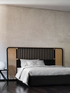 a bed with white sheets and pillows in a room next to a lamp on a table