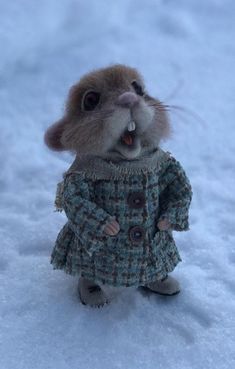 a small stuffed animal is standing in the snow wearing a coat and boots with its mouth open