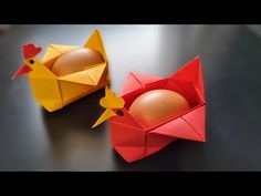 two origami chickens and an egg in a carton on a black table