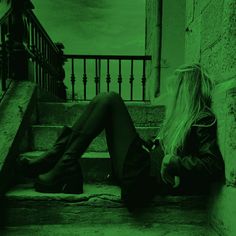 a woman sitting on the steps in front of stairs with her legs crossed and looking down