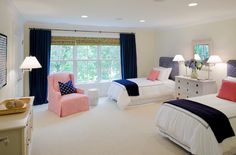 two beds in a room with blue curtains and white carpeted walls, along with pink chairs