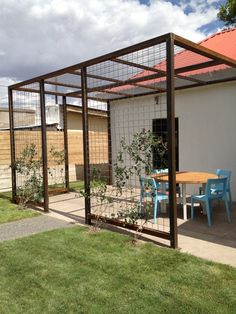 an outdoor dining area with blue chairs and a wooden table in the middle of it