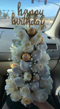 a bouquet of flowers sitting in the front seat of a car with happy birthday written on it