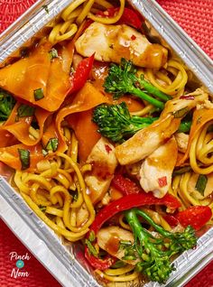 chicken and veggie stir fry in a pan on a red tablecloth with chopsticks