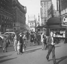 an old black and white photo of people walking in the street