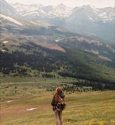 a woman standing on top of a lush green hillside