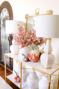 a white table topped with vases filled with flowers next to a mirror and lamp