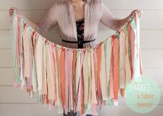 a woman is holding up some colorful streamers on her waist and the words make a fabric banner in front of her