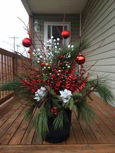 a potted plant sitting on top of a wooden deck covered in christmas decorations and balls