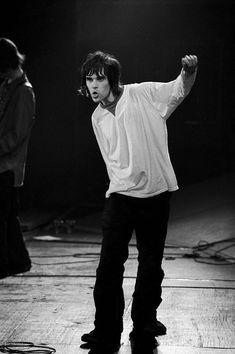 the rolling stones performing on stage in front of two other musicians, one holding his arm up